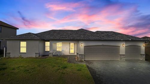 a house with a garage with a cloudy sky at The Cape Escape Pet-Friendly Sleeps 7 in Cape Coral