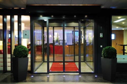 an open glass door in a building with a red carpet at Sorell Hotel Ador in Bern