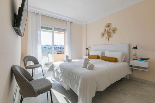 Un dormitorio blanco con una cama grande y una ventana en Luminous apartment in Puerto Banús, Marbella en Marbella