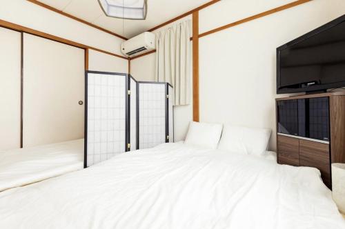 a bedroom with a bed and a flat screen tv at K-House in Kamakura