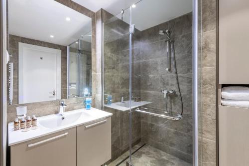 a bathroom with a shower and a sink and a mirror at Alliance Palace By Marriott in Batumi