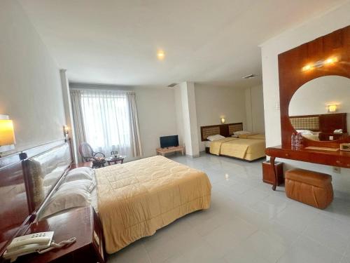 a hotel room with two beds and a mirror at Hotel Wisata Indah Sibolga in Sibolga