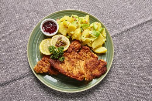 a plate of food with chicken and potatoes and fruit at Hotel & Restaurant Burgschänke in Kaiserslautern