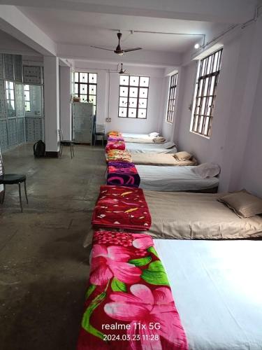 a row of beds are lined up in a room at Muzaffarpur Guest House in Muzaffarpur
