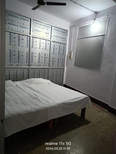 a room with a bed and a wall with a window at Muzaffarpur Guest House in Muzaffarpur