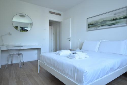 a white bedroom with a white bed and a mirror at Welc-ōM Padova Santa Sofia in Padova