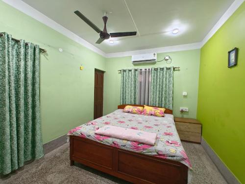 a bedroom with a bed with green walls and a ceiling at Anjali Homestay in Siliguri