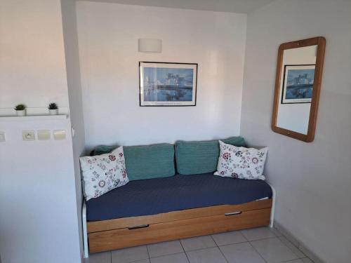 Cette chambre comprend un canapé avec des oreillers et un miroir. dans l'établissement Primavera 115, T2 avec piscine, parking à 300m plage, au Cap d'Agde