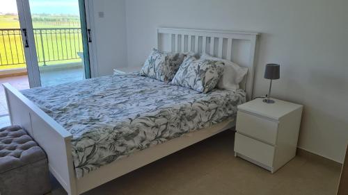 a bedroom with a bed with a night stand and a window at The Olive Grove Escape, Eleonas Apts in Sotira