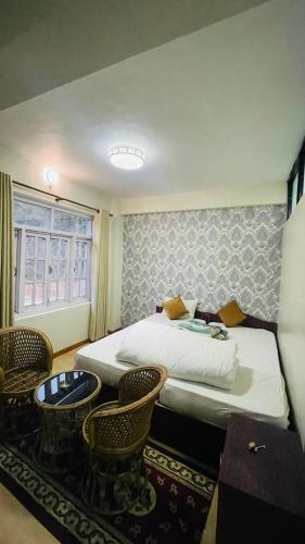 a hotel room with two beds and a table and chairs at Hotel peace point dhulikhel in Dhulikhel