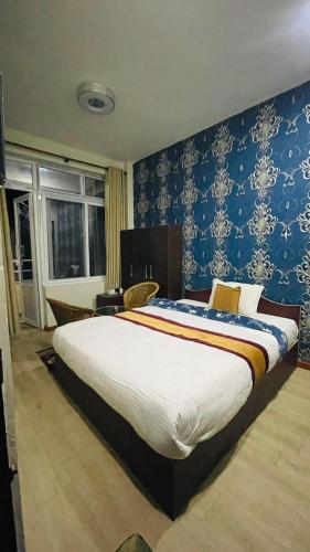 a bedroom with a large bed with blue wallpaper at Hotel peace point dhulikhel in Dhulikhel