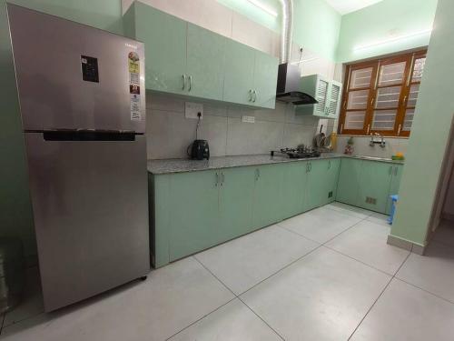 een keuken met groene kasten en een roestvrijstalen koelkast bij Happy HomeStay In Pondicherry in Pondicherry