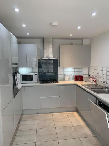 a large kitchen with white cabinets and appliances at The Chestnuts in Winscombe