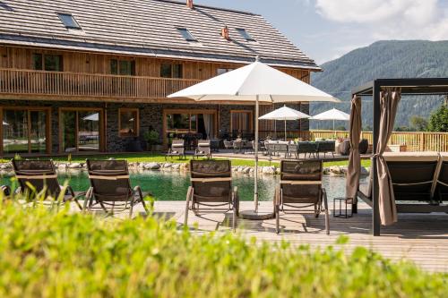 a group of chairs and umbrellas next to a pool at Lerchpeuntgut Almchalets in Tamsweg