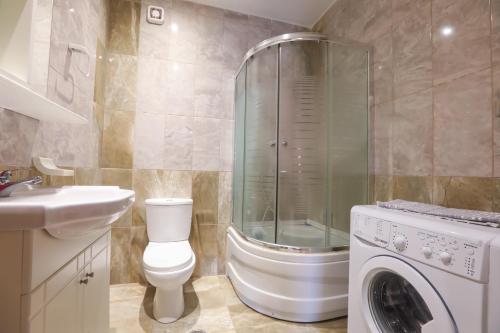 a bathroom with a toilet and a shower and a washing machine at Kerkyra Beach Hotel & Apartments in Benitses