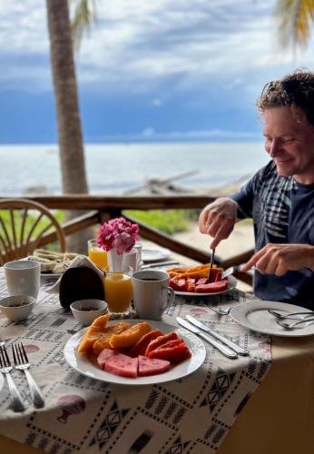 een man aan een tafel met een bord eten bij Barry's Beach Resort in Mkwaja