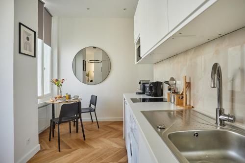 - une cuisine avec un évier et une table avec un miroir dans l'établissement Studio Arc de Triomphe by Studio prestige, à Paris