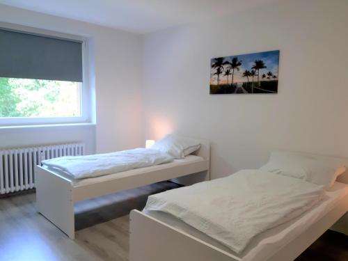 Duas camas num quarto branco com uma janela em Chic Apartment with Balcony em Gelsenkirchen