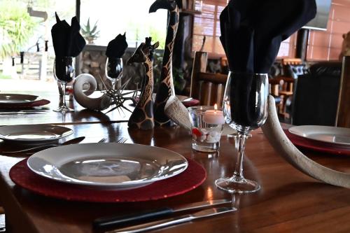 a wooden table with a plate and wine glasses on it at Aloegrove Safari Lodge in Otjiwarongo
