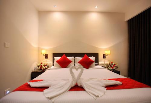 a bedroom with a white bed with red pillows at HOTEL SAN in Kollam