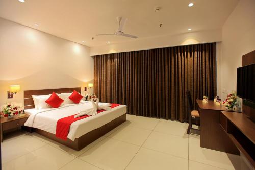 sypialnia z dużym łóżkiem z czerwonymi poduszkami w obiekcie HOTEL SAN w mieście Kollam