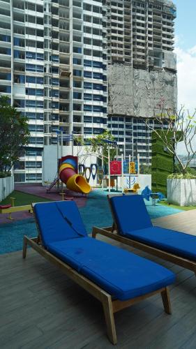 a pool with two blue lounge chairs and buildings at Reizz Residence by Elysium in Kuala Lumpur