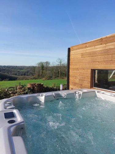une baignoire jacuzzi en face d'un bâtiment en bois dans l'établissement La Cabane D'Emma Spa&Sauna privé, à Bannalec