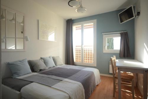 une chambre avec un lit, un bureau et des fenêtres dans l'établissement Appartement plage piscine et tennis inclus, à La Londe-les-Maures
