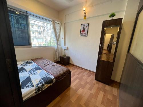 een slaapkamer met een bed, een raam en een spiegel bij Sixth Sense Lokhandwala in Mumbai