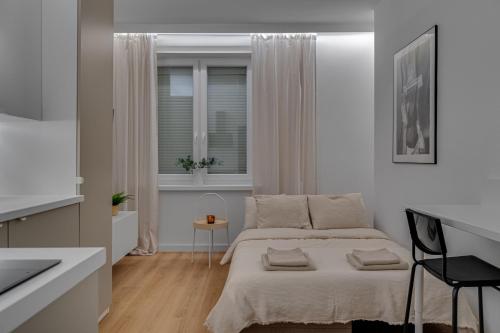a white bedroom with a bed and a window at Hann Haven Apartments Armii krajowej 16 in Opole