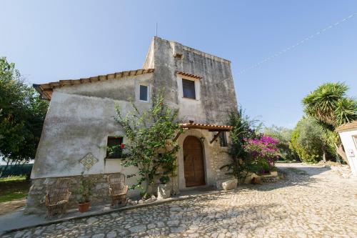 an old stone house with a door and flowers at Agriturismo Masseria Pozzo in Sperlonga