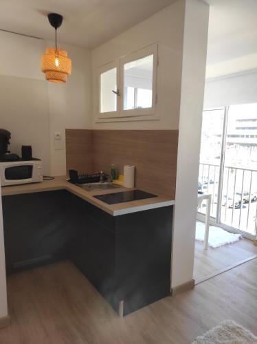 une cuisine avec un évier et un micro-ondes dans l'établissement Résidence Richelieu port position centrale studio cosy 2 adultes piscine place de parking privative vue Mont Saint Martin, au Cap d'Agde