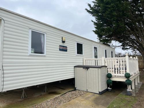 a white trailer with a porch and a fence at Primrose valley - Primrose Field 46 holiday home in Filey