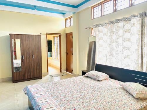a bedroom with a bed and a large window at Serene Homestay in Sibsāgar