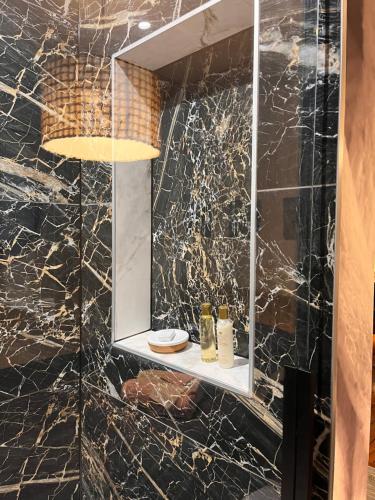 een badkamer met een marmeren muur en een spiegel bij La Maison Bateau au Bord de Mer in Guissény