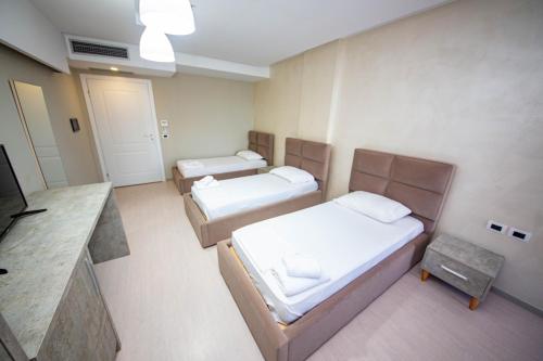 a room with three beds and a tv in it at Hotel Miki in Durrës