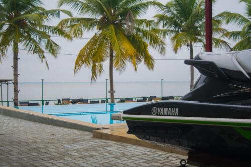 ein Boot, das neben einem Pool mit Palmen parkt in der Unterkunft New saniro Lagoon Deck in Katunayaka