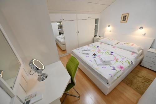 a small white bedroom with a bed and a desk at Apartment Eva in Zadar