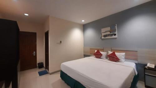 a bedroom with a large white bed with red pillows at Hotel Cepu Indah 2 in Cepu