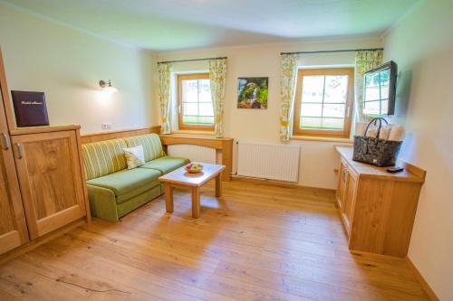 ein Wohnzimmer mit einem grünen Sofa und einem Tisch in der Unterkunft Forsterhof in Ramsau am Dachstein