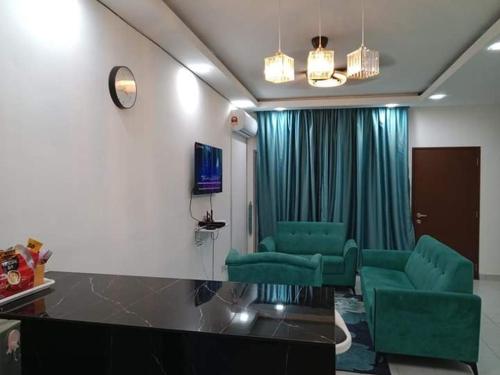a living room with green chairs and a television at Iyad Guest House in Banting