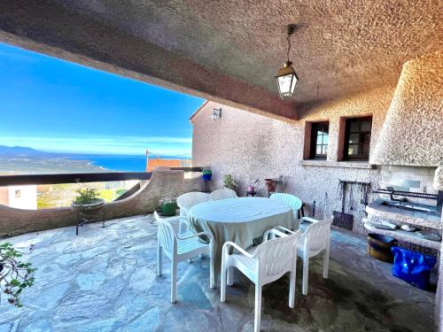 un patio avec une table, des chaises et une cheminée dans l'établissement Maison de village vue mer et montagne, à Sari-Solenzara