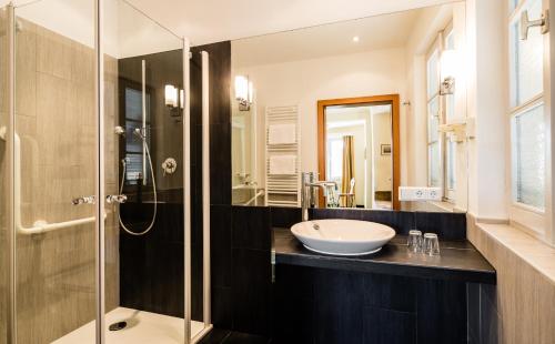 a bathroom with a sink and a glass shower at Hotel Traube in Bressanone