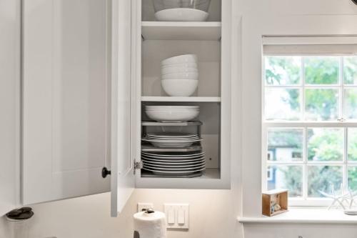 a kitchen cabinet with plates and bowls and a window at The Garden Downtown Steps to Waterfront in Newburyport