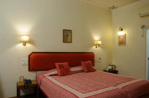 a bedroom with a red bed with two pillows at Hotel Arya Niwas in Jaipur