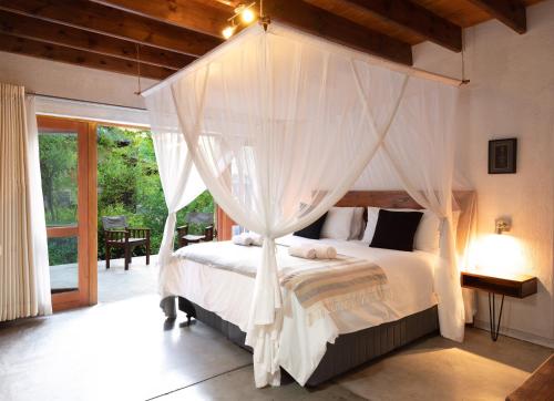 1 dormitorio con cama con dosel y cortinas blancas en Bush Villas on Kruger en Phalaborwa