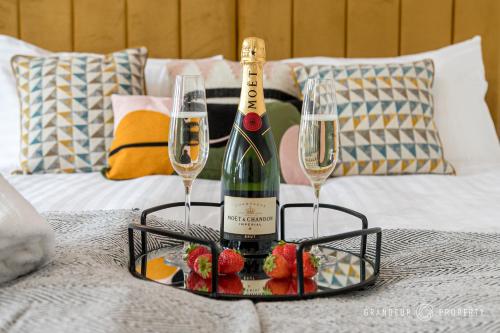 a bottle of champagne and two glasses on a bed at Spacious & modern 3 bed, 10 min to beach, parking - Lyell House in Poole