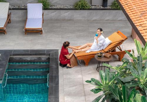 dos mujeres sentadas en un banco junto a una piscina en Jasmine City Hotel, en Bangkok