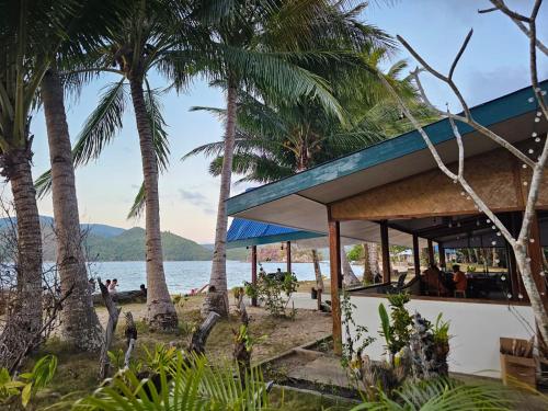 un edificio en la playa con palmeras en DK2 Resort - Hidden Natural Beach Spot - Direct Tours & Fast Internet, en El Nido