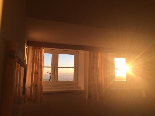 a window in a room with the sun shining through at Lodge am Krippenstein in Obertraun